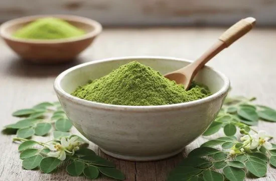 Dried moringa leaves and green moringa powder on dark slate