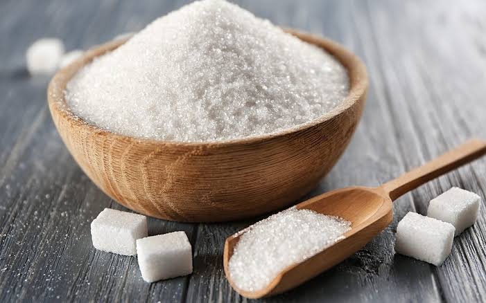 Refined white crystal sugar in a dark bowl