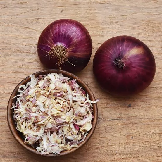 Dehydrated onion flakes and onion powder on dark slate